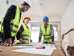 Construction professionals reviewing ALTA survey plans and renovation documents inside an existing commercial building before redevelopment planning.