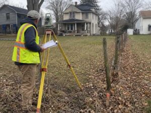 Land surveyor in Columbus Ohio reviewing property records and field evidence to resolve conflicting tax map and deed information.